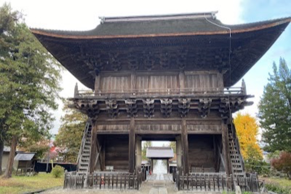 Stone-paved Zenringai temple street lined with historic wooden gates in Hirosaki