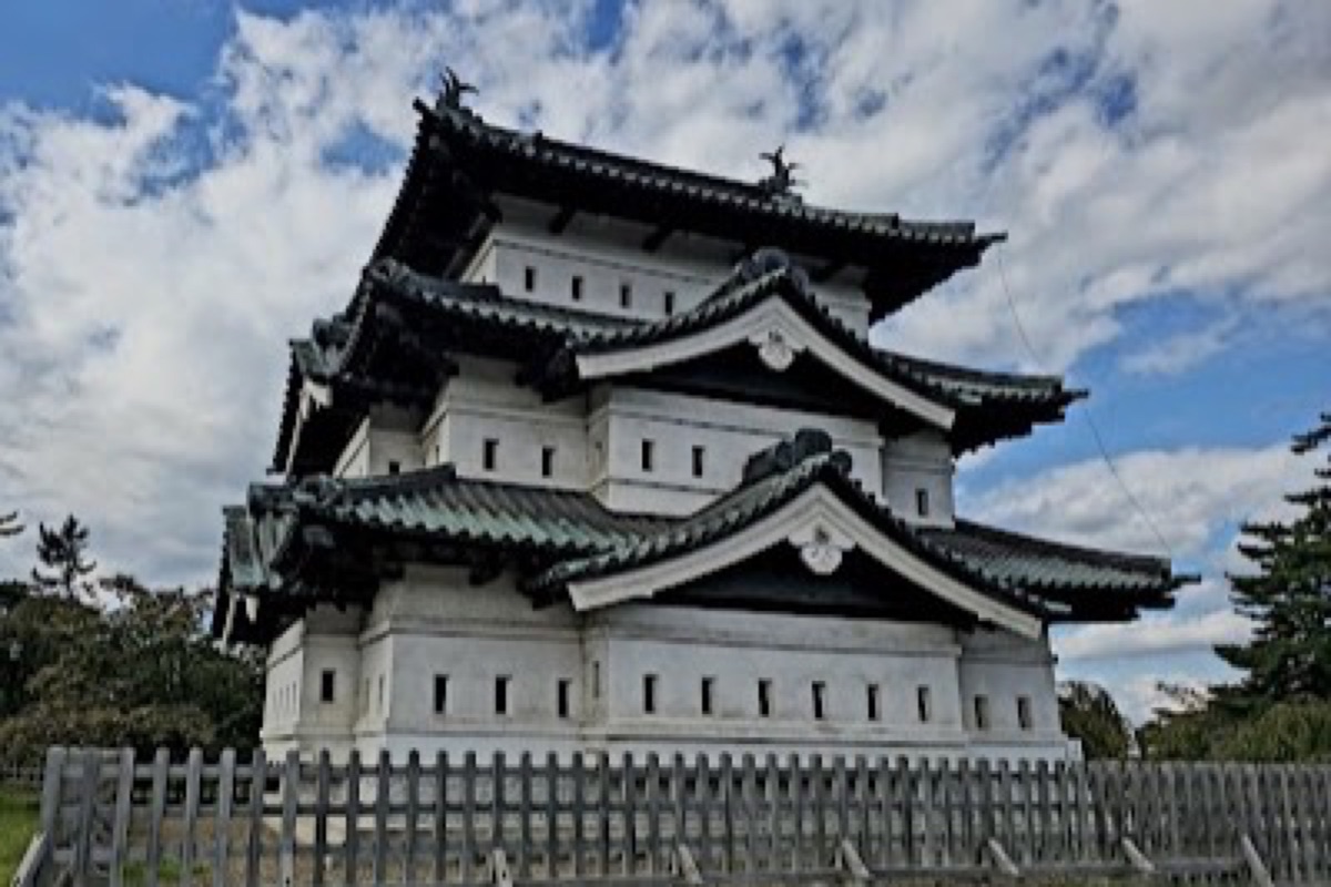 Hirosaki Castle keep framed by blooming cherry trees along the historic moats