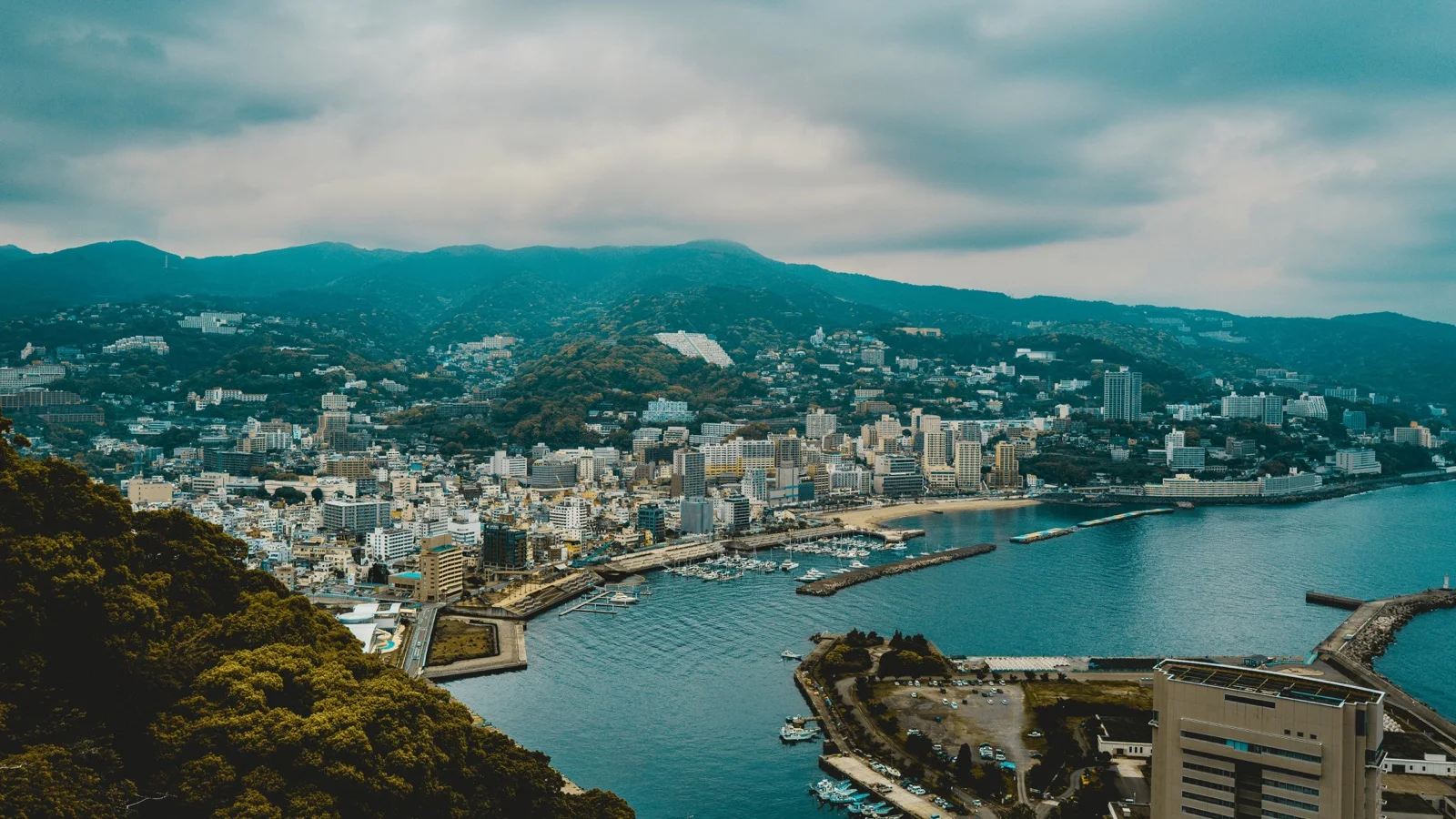 Palm-lined Sun Beach promenade along Sagami Bay with the Atami hills in the background