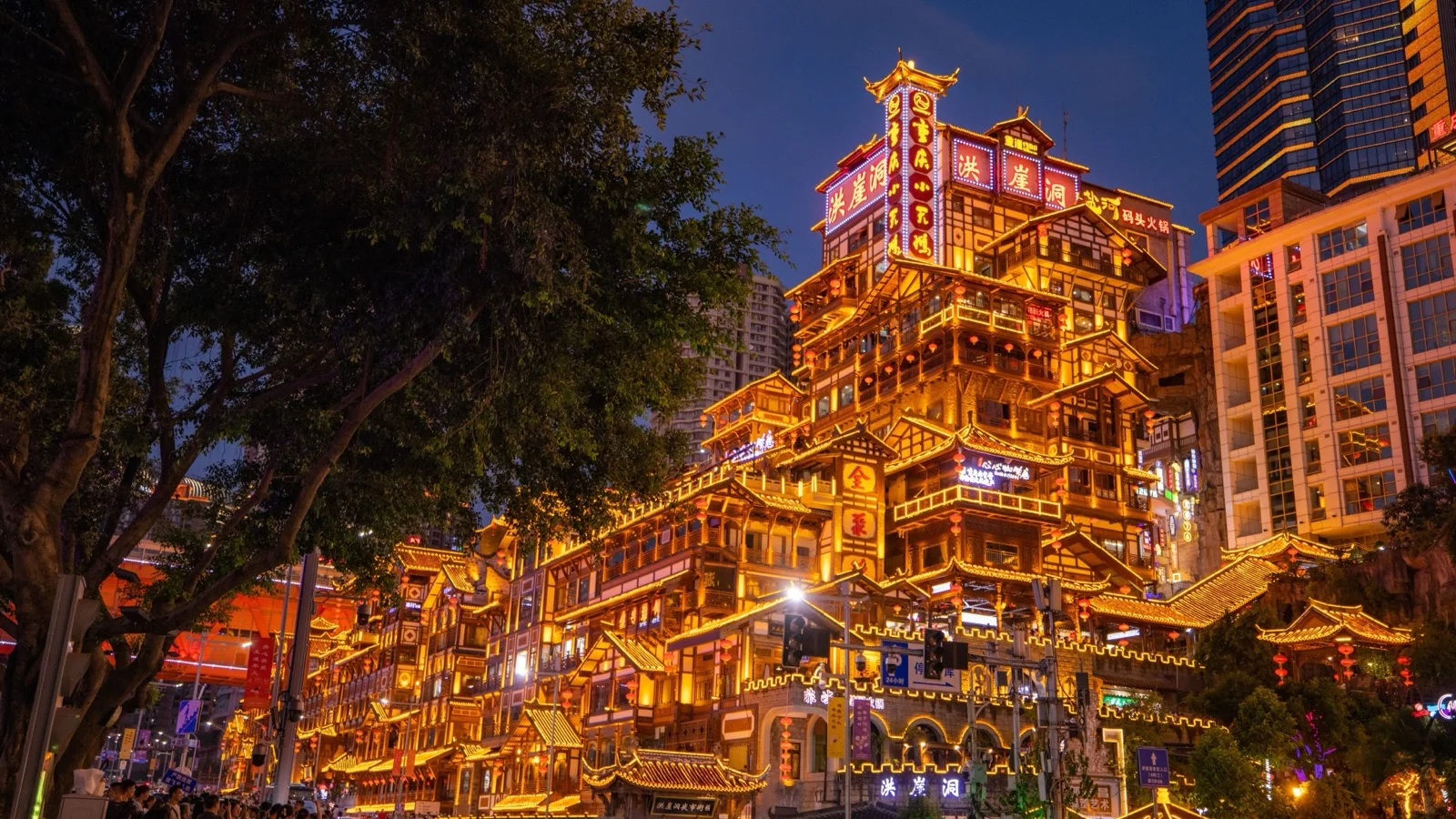 Night view of Hongyadong in Chongqing, China, with golden stilt houses glowing above the Jialing River