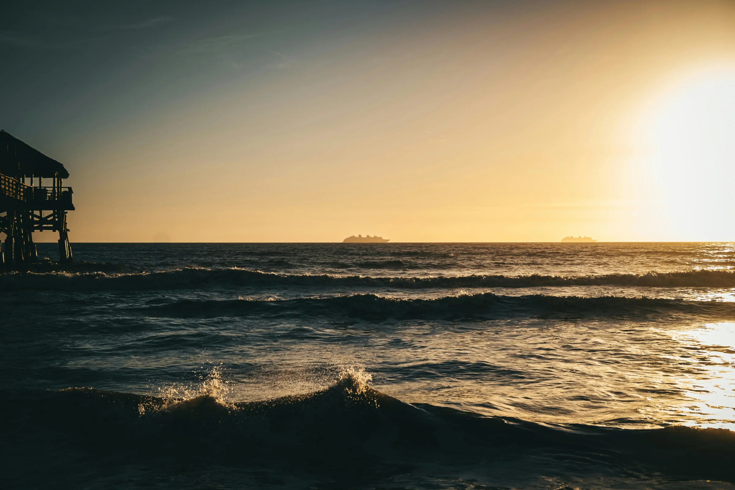Aerial sunrise view of Cocoa Beach shoreline and pier in Florida.