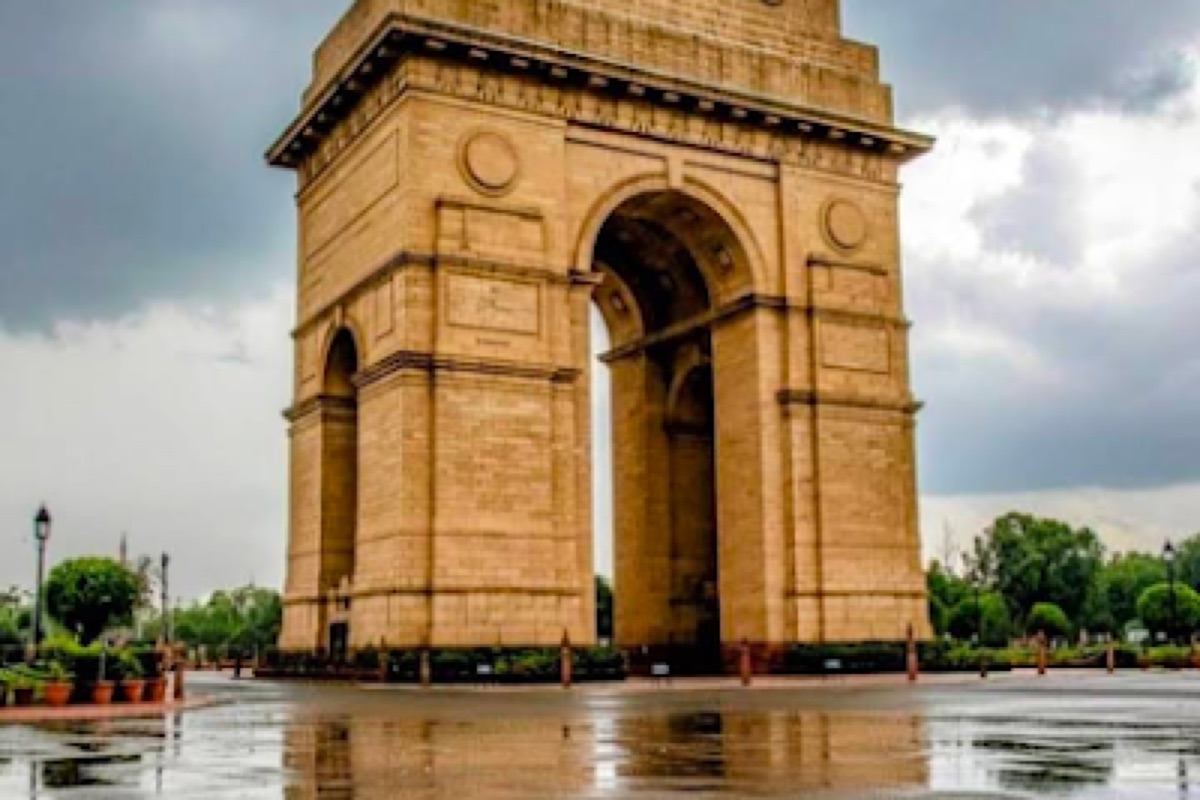 The India Gate war memorial arch lit by golden hour light above its lawns in New Delhi