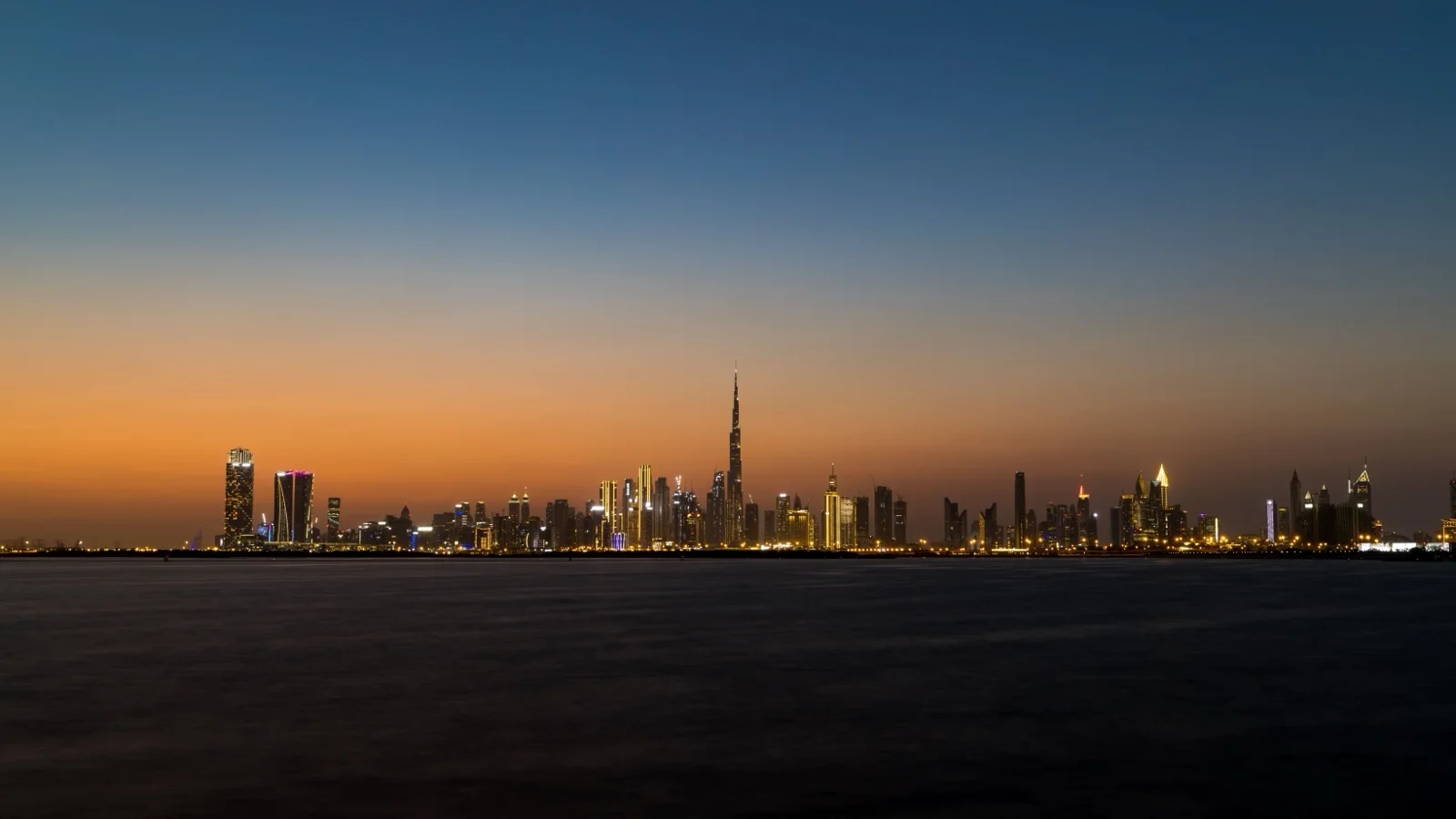 Burj Khalifa and the Downtown Dubai skyline above Burj Lake at sunset
