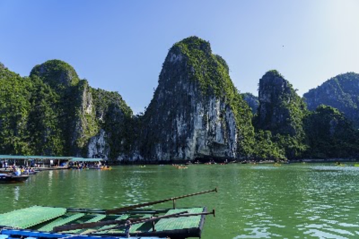 Plank boat gliding past floating houses and pearl farms at Cua Van Floating Village