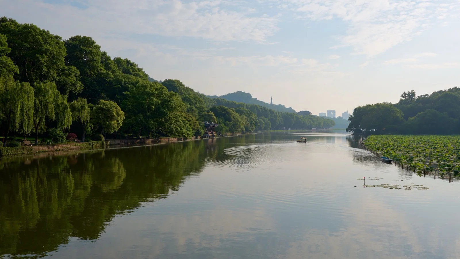 Spring view of West Lake in Hangzhou with willows and peach blossoms along the causeway and Leifeng Pagoda in the distance