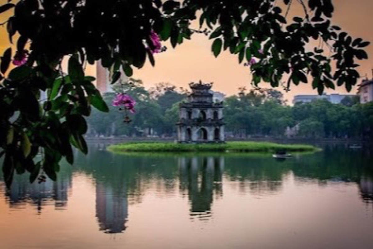 Hoan Kiem Lake with Turtle Tower reflected in calm turquoise water at sunrise