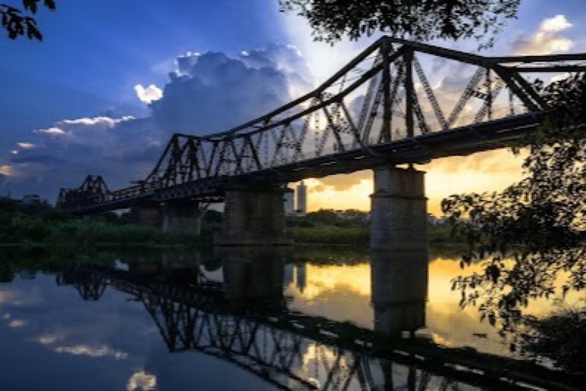 Long Bien Bridge steel cantilever silhouette over the Red River at sunset