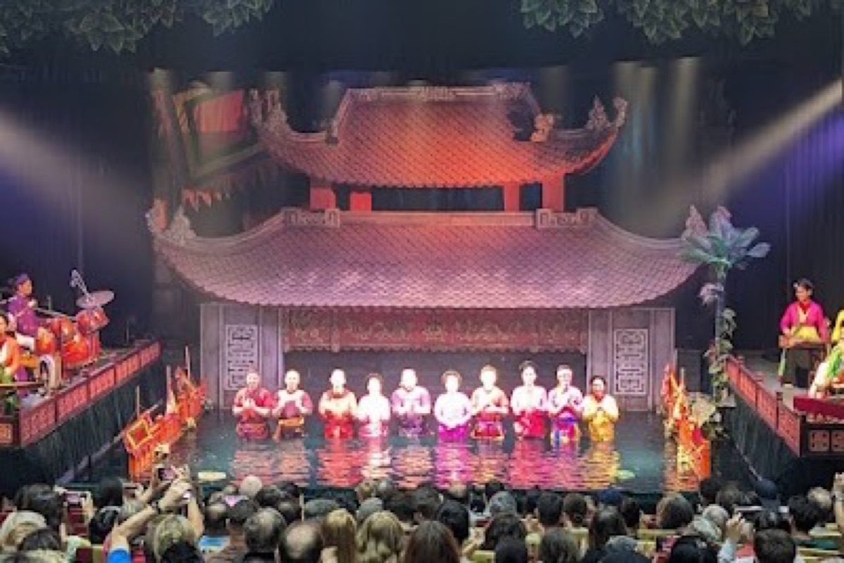 Water puppet performers on the lit water stage at Thang Long Water Puppet Theatre