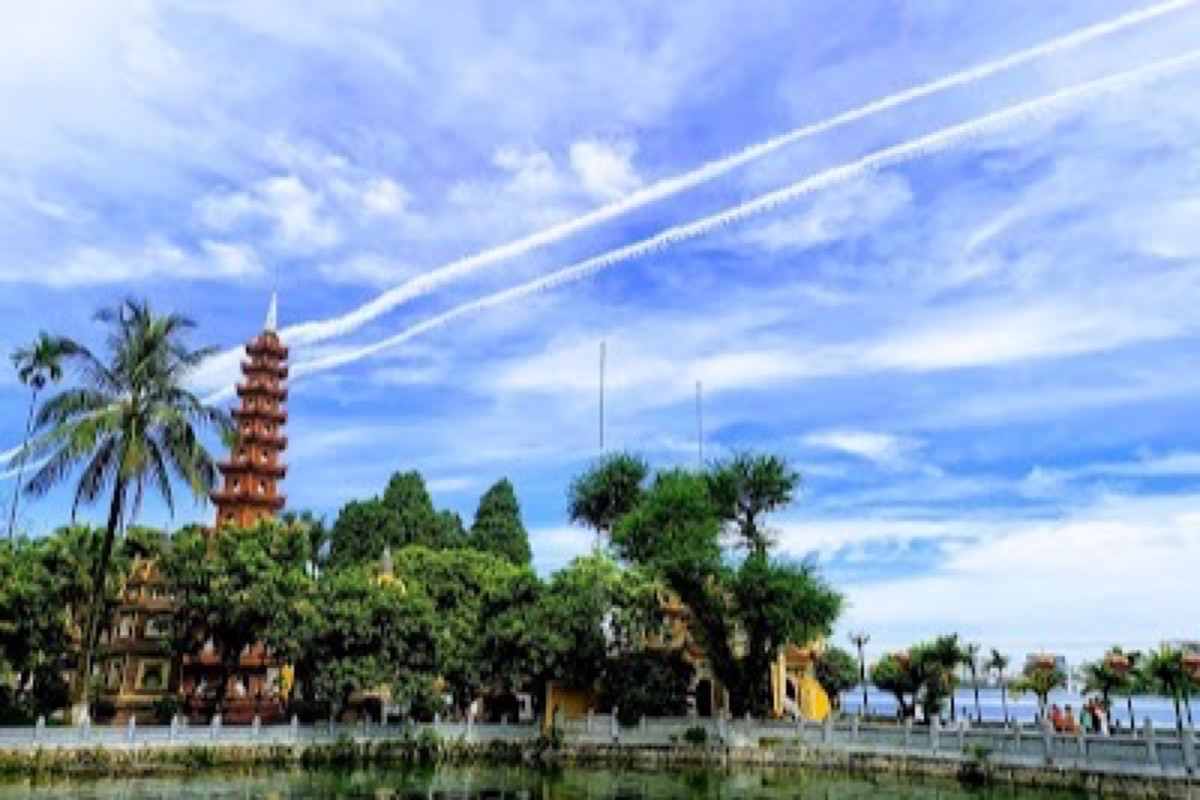 Red and gold Tran Quoc Pagoda silhouetted over West Lake at golden hour
