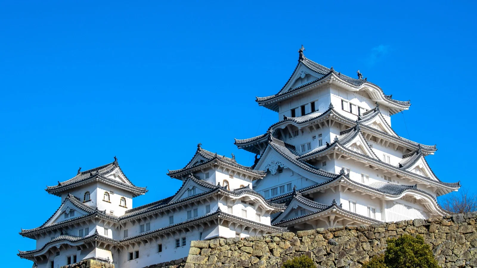 Himeji Castle's white multi-story keep rising above the moat under a clear sky