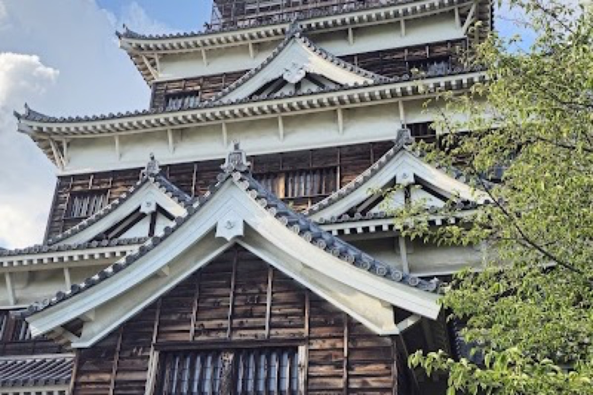 Hiroshima Castle keep reflected in the moat with autumn foliage