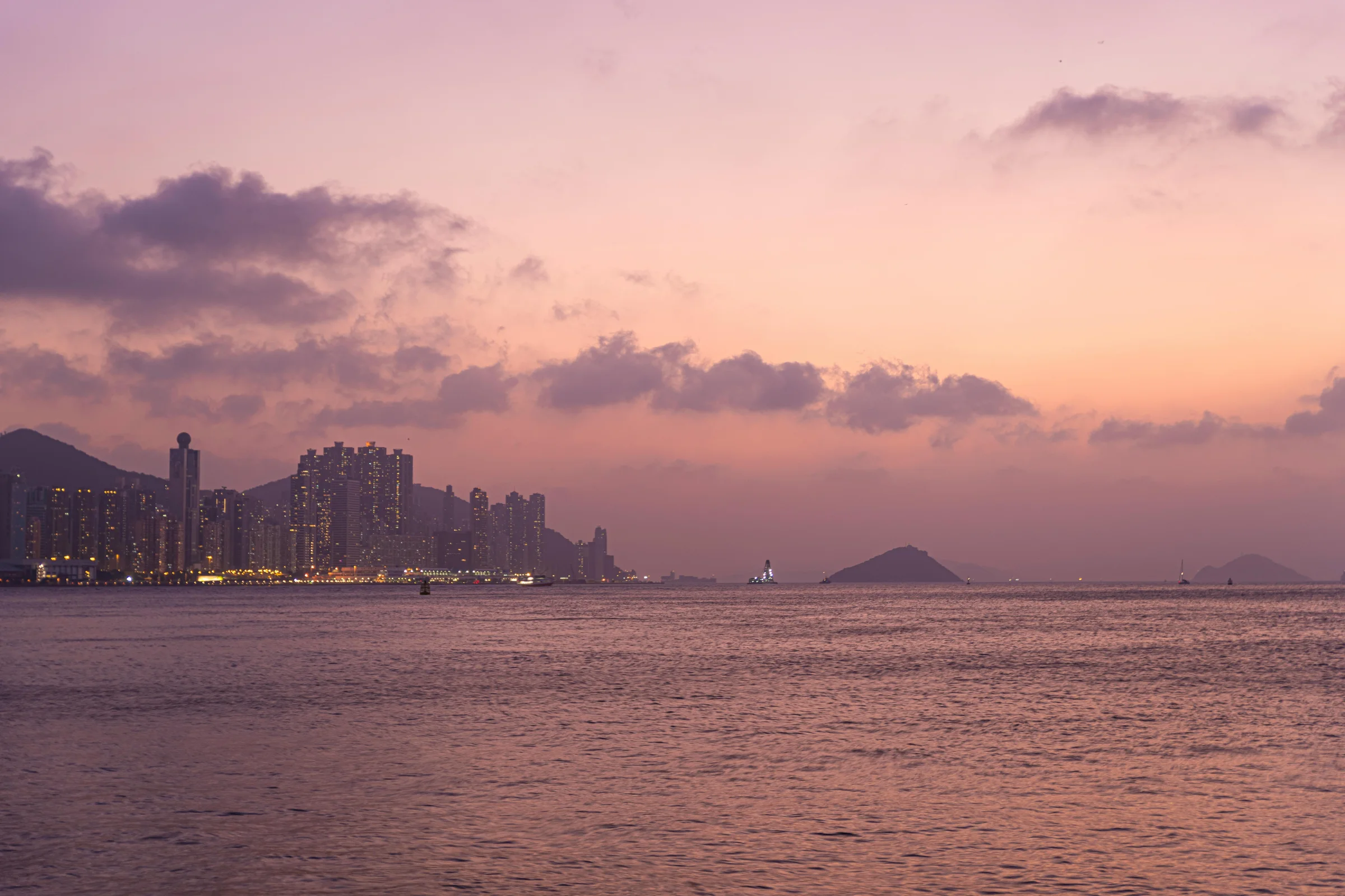 Hong Kong skyline and Victoria Harbour at sunset with illuminated skyscrapers