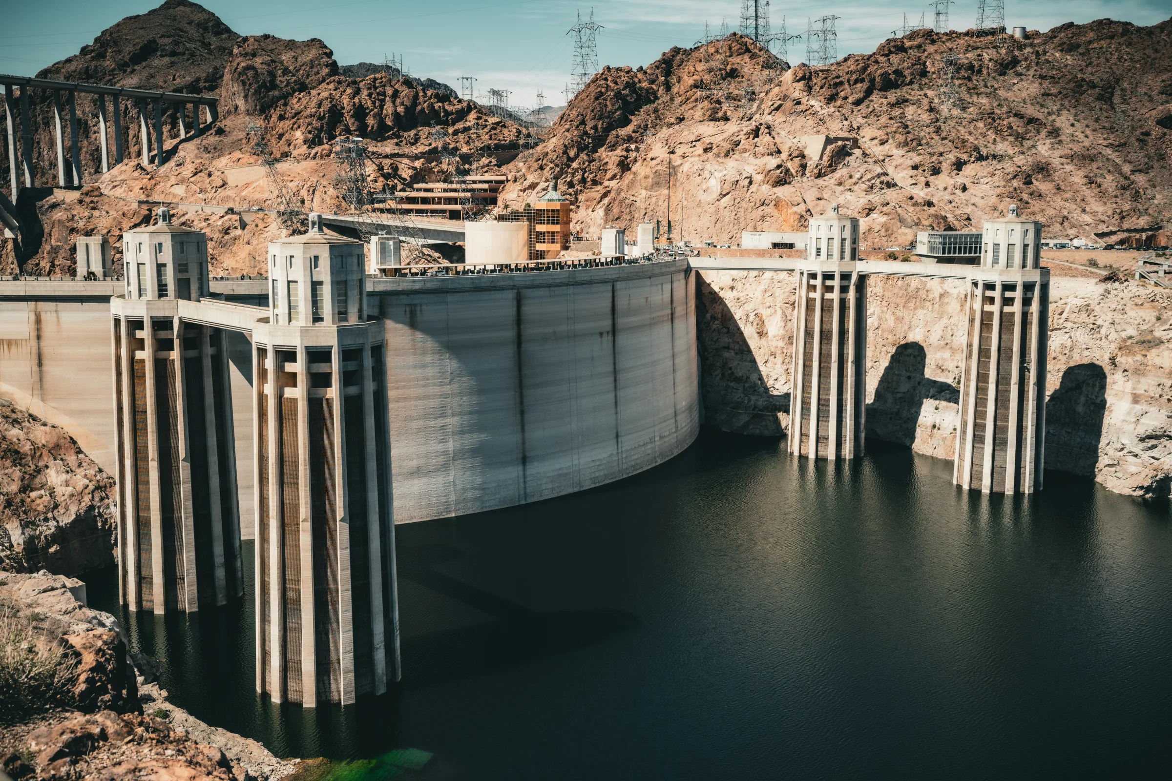 Aerial hero view of Hoover Dam spanning the Colorado River with desert landscape.