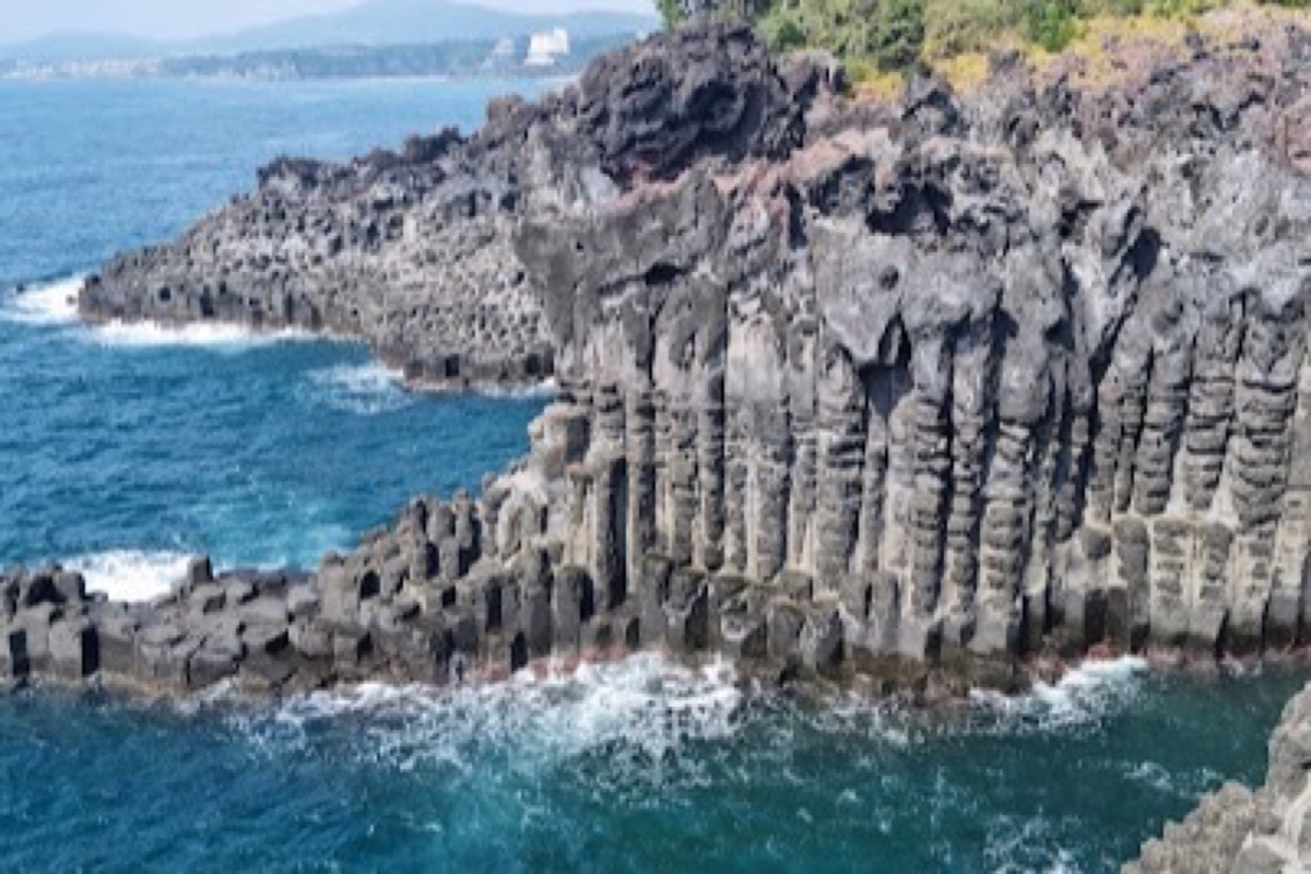Jusangjeolli Cliff hexagonal basalt columns with waves crashing in Seogwipo, Jeju