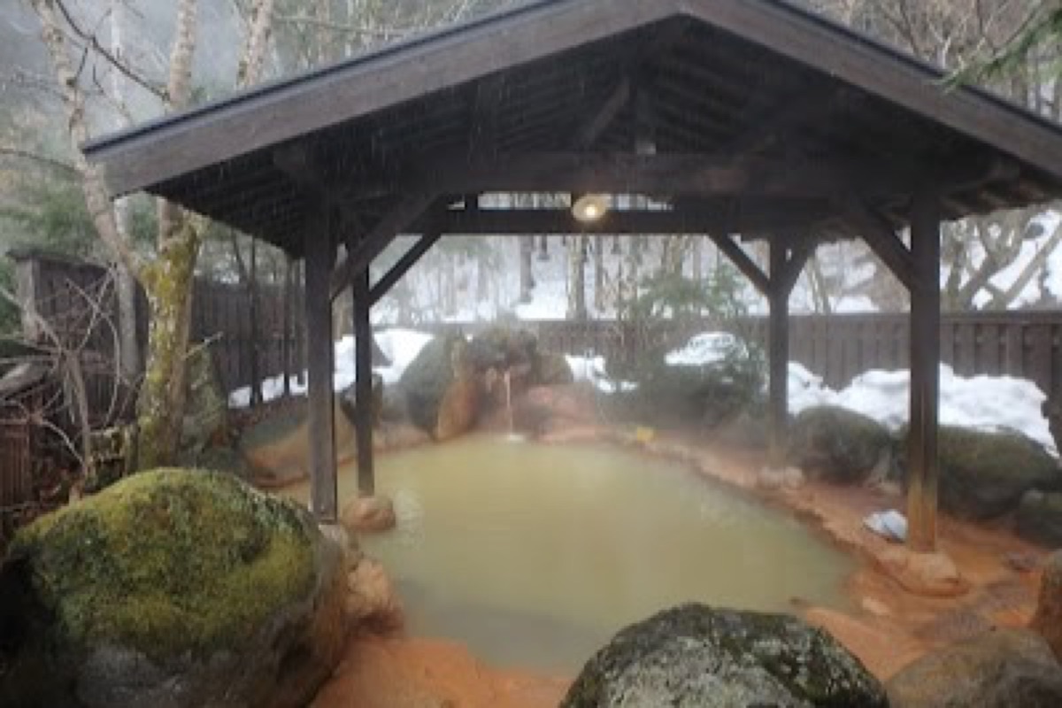 Hirayu Onsen outdoor hot spring baths with steam rising among misty mountain peaks