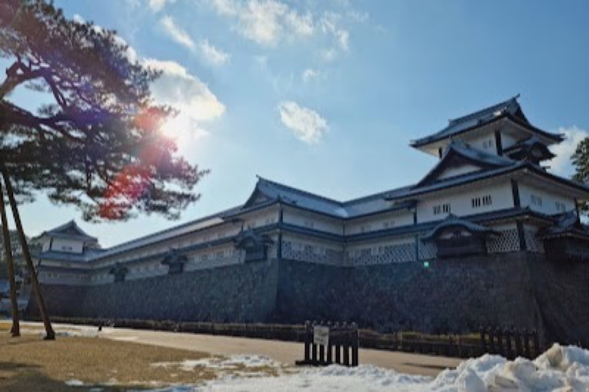 Ginkgo-lined path leading to restored turrets at Kanazawa Castle Park in autumn