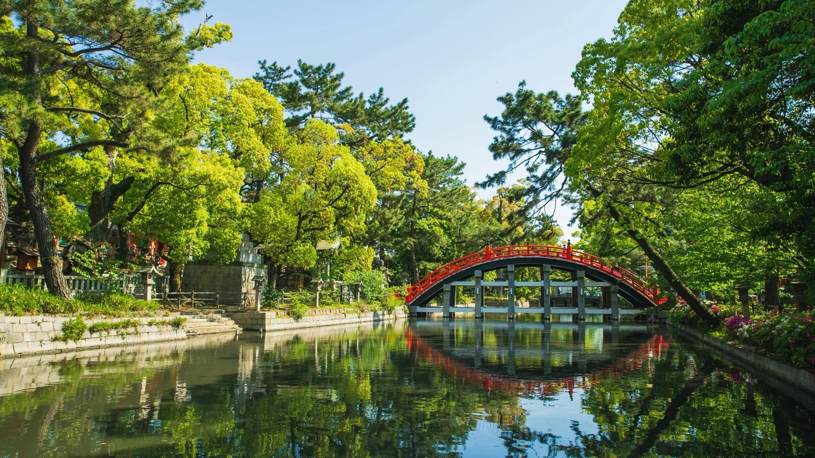Willow-lined Otani River canal at dusk with stone bridges and lantern light in Kinosaki Onsen