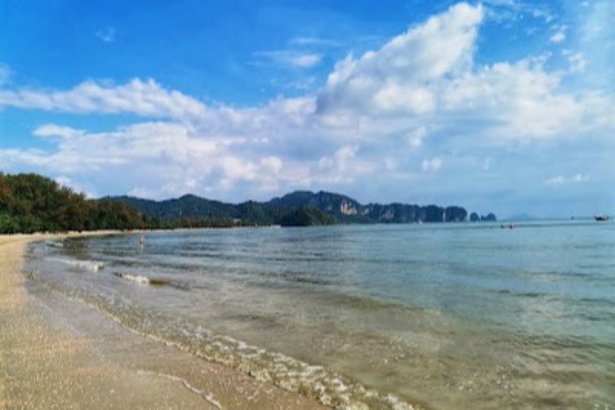 Casuarina trees and longtail boats along Noppharat Thara Beach at sunset near Ao Nang