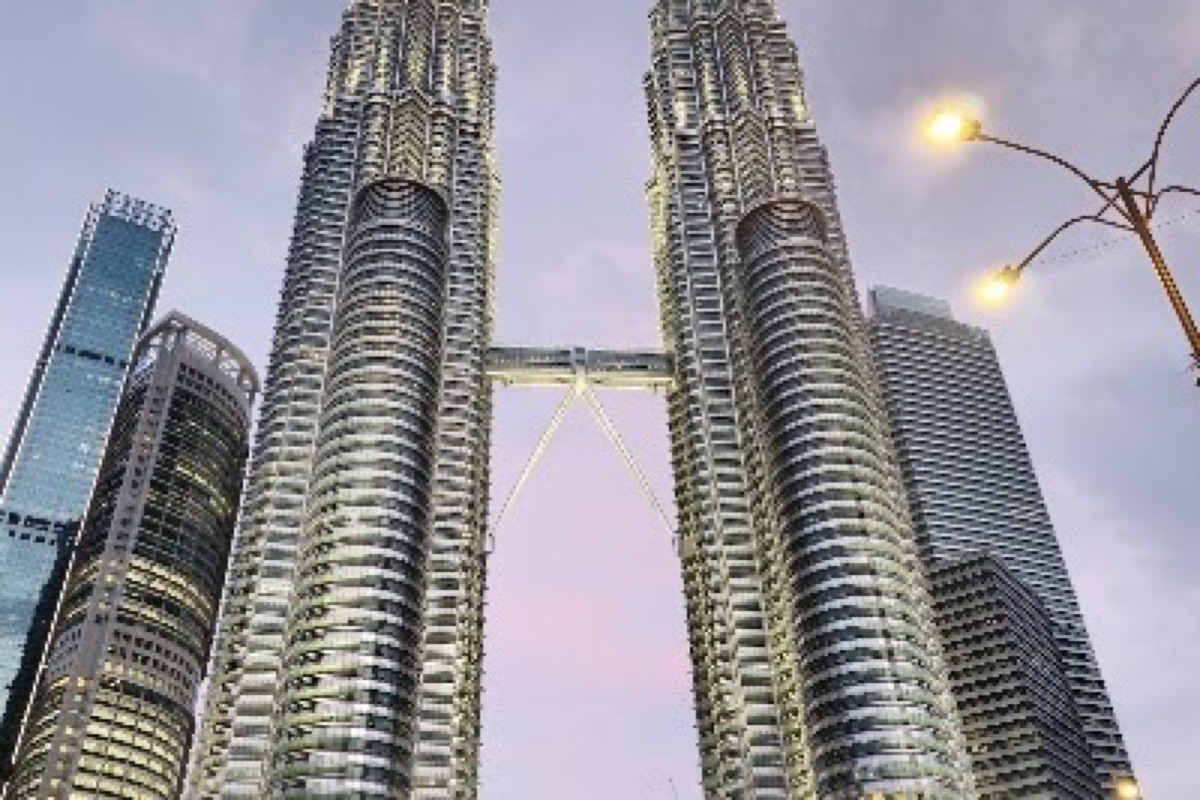 Petronas Twin Towers lit up at golden hour above the KLCC lakefront promenade