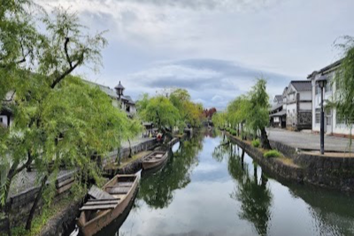 Kurashiki Bikan Historical Quarter canal with willow trees and white-walled storehouses at dawn