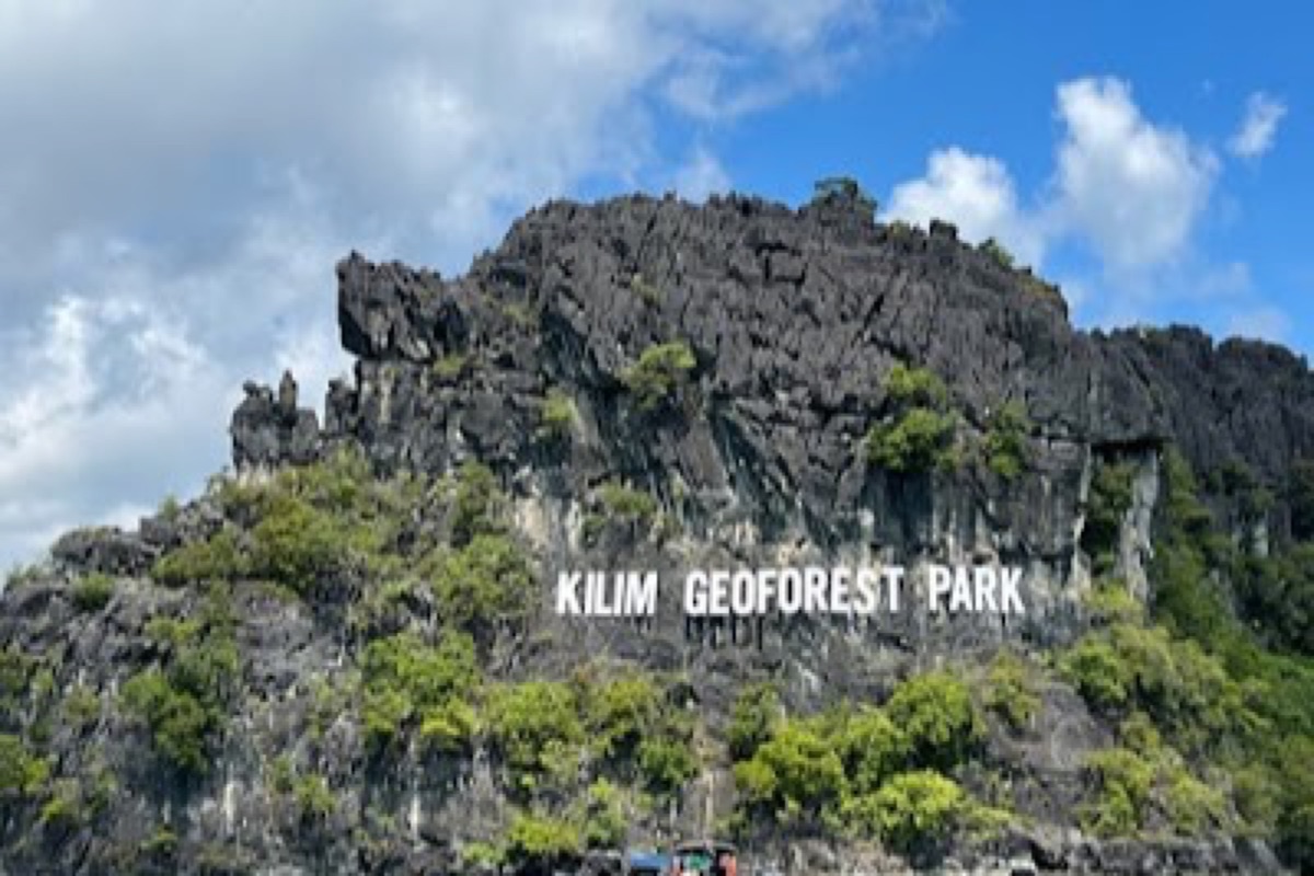 Wooden boat drifting through mangrove channels and limestone karsts at Kilim Geoforest Park