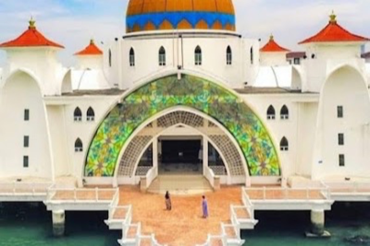 Melaka Straits Mosque glowing at sunset above the water on Pulau Melaka