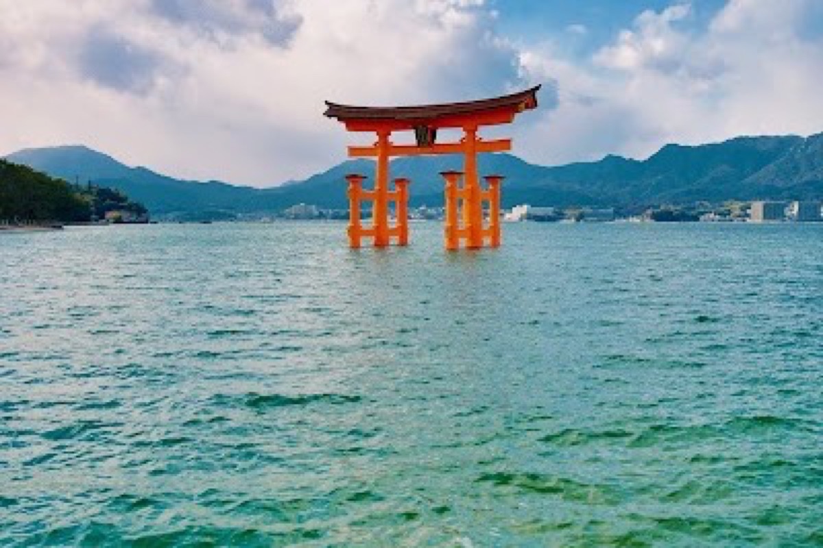The vermilion O-Torii Gate standing in shallow bay waters at Miyajima at low tide
