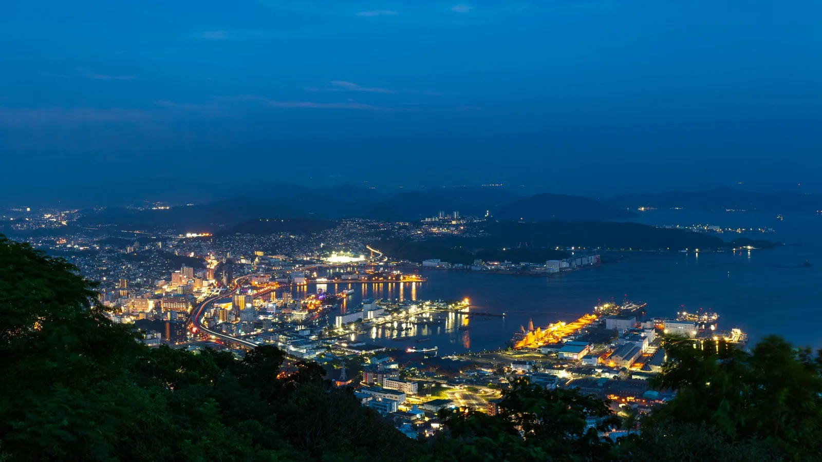 Nagasaki harbor and hillside cityscape glowing at dusk from a Minami-Yamate viewpoint