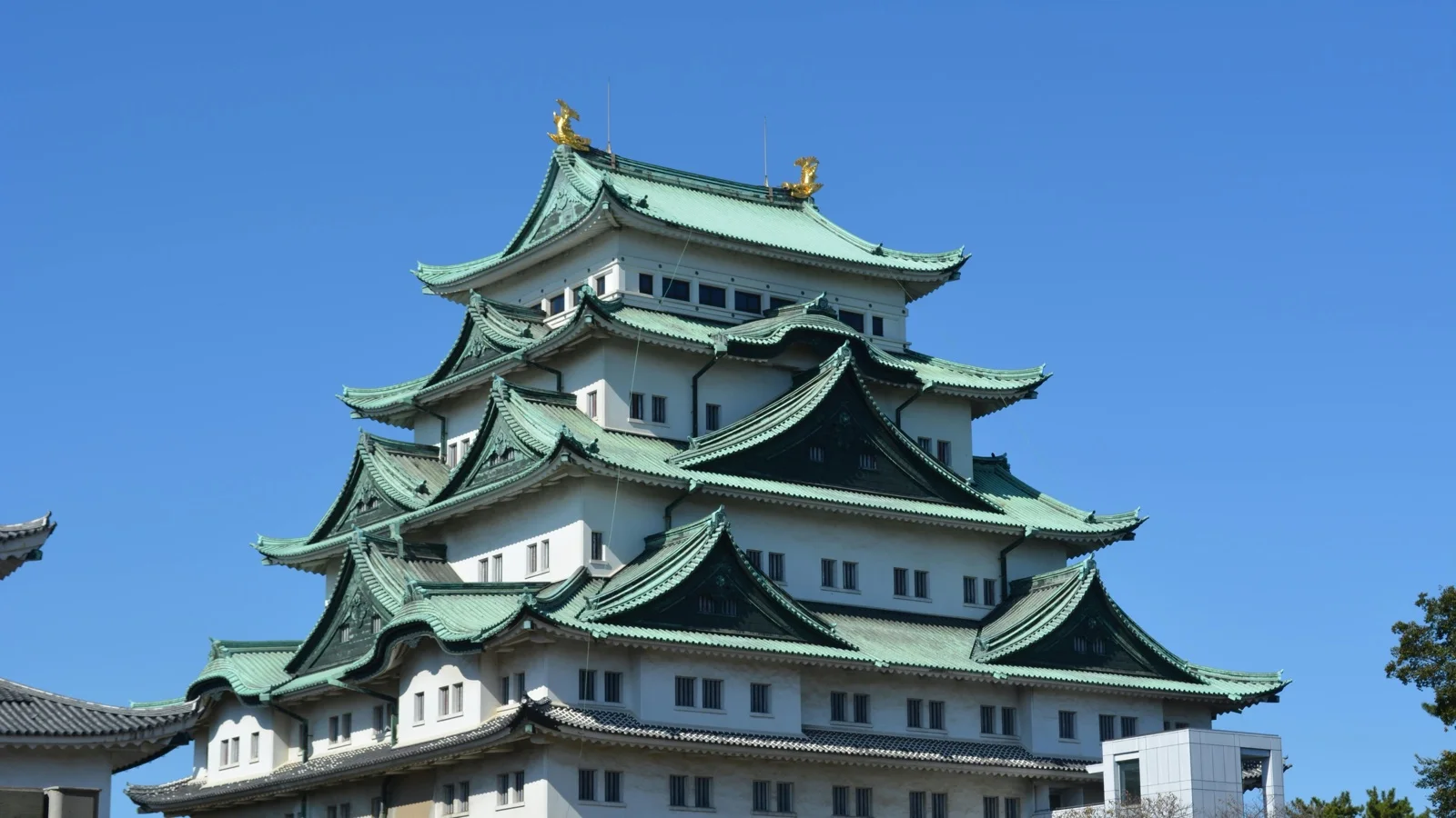 Nagoya Castle keep with golden shachihoko rooftop ornaments against an autumn sky