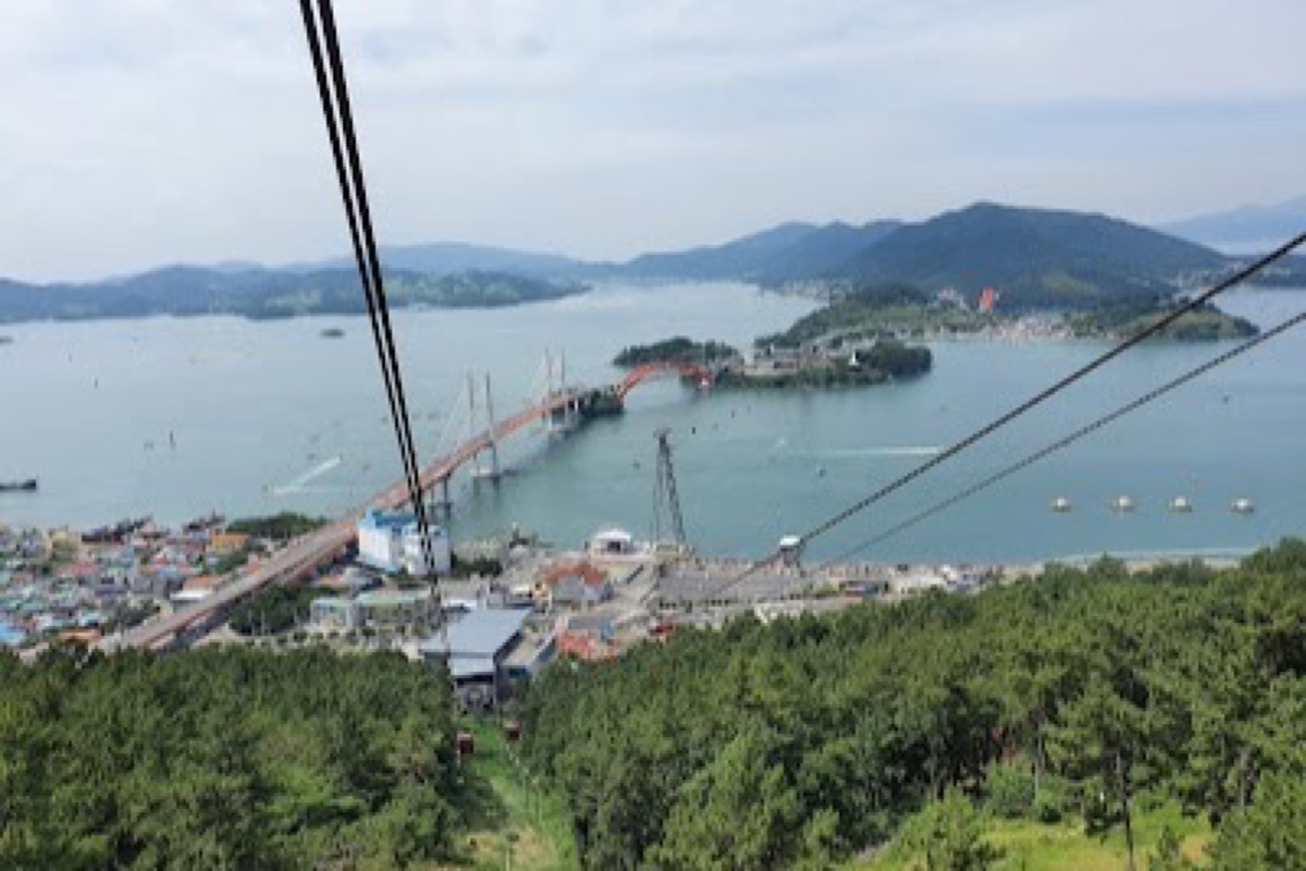 Sacheon Cable Car gondola above the coastline with aerial views toward Namhae's peaks