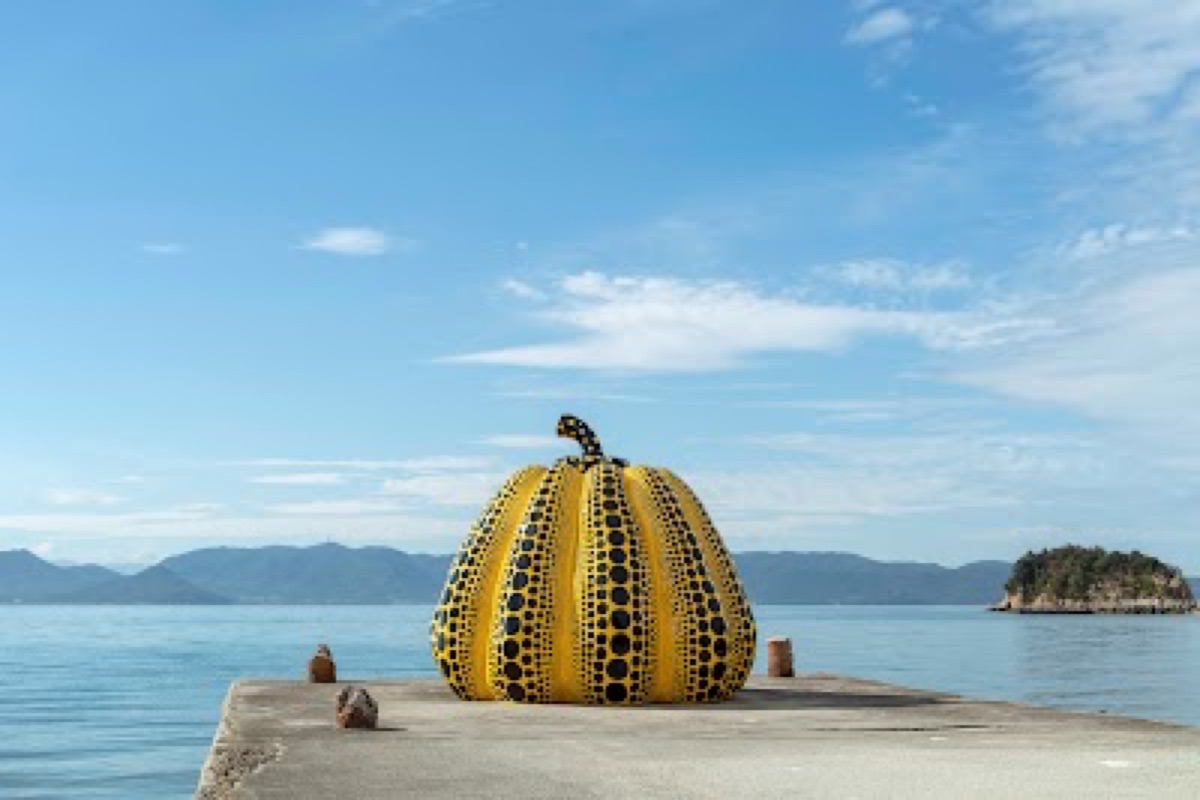 Yayoi Kusama Yellow Pumpkin sculpture on the Naoshima waterfront at golden hour