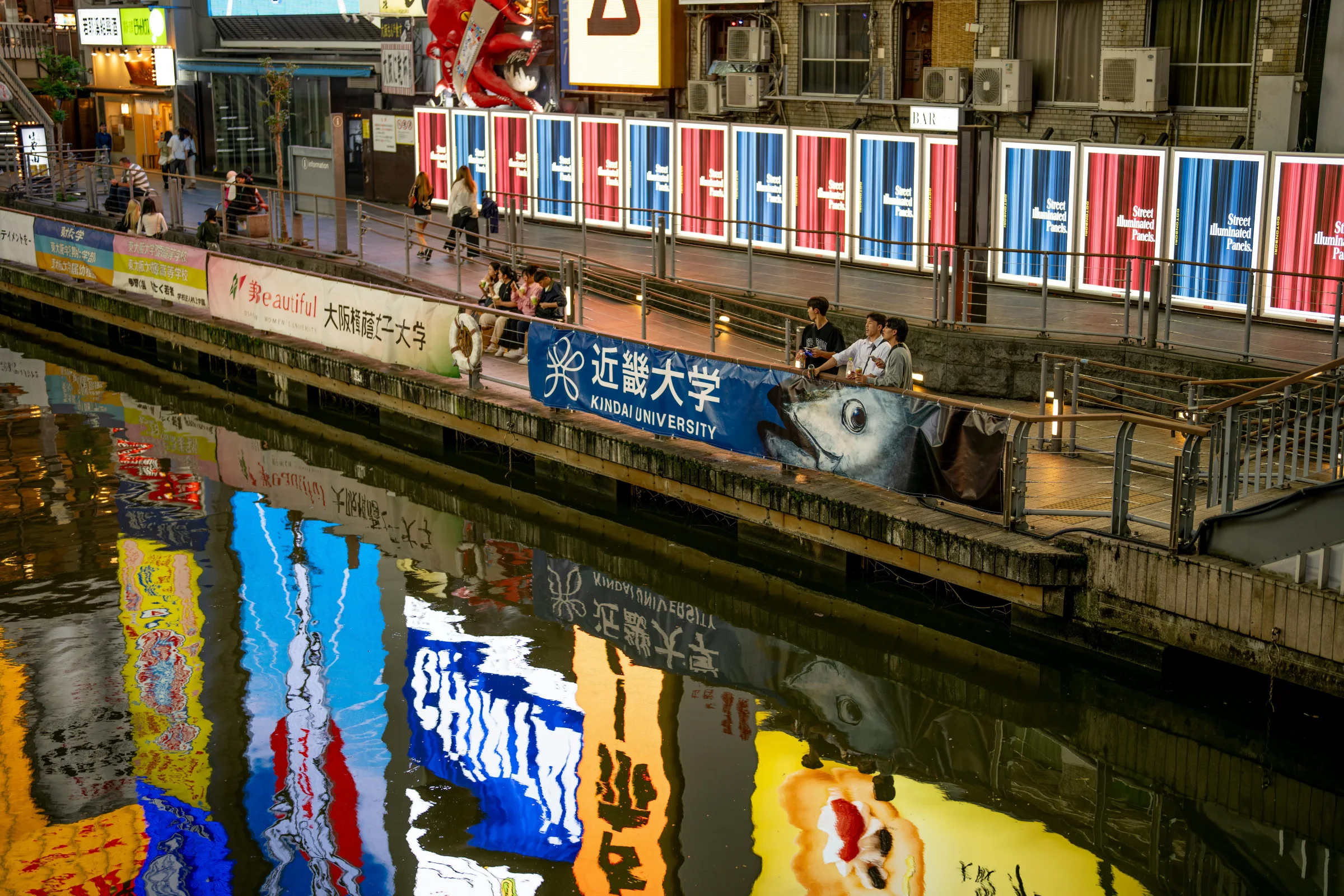 Night view of Osaka's Dotonbori canal with bright city lights and skyline.
