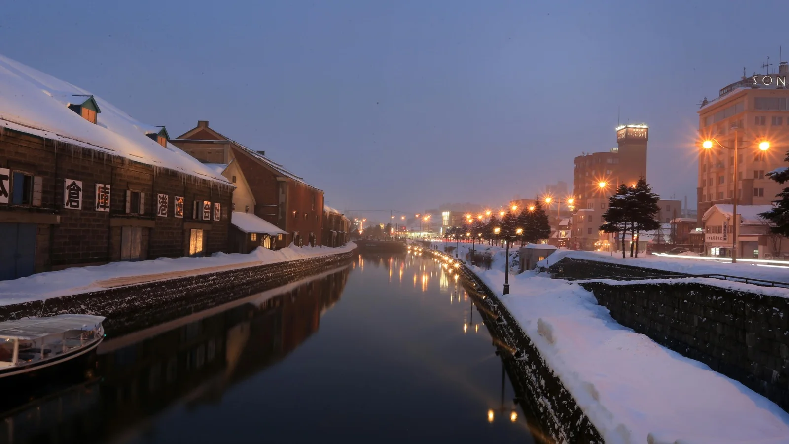 Otaru Canal at golden hour with gas lamps reflecting off the stone-walled waterway and restored warehouses
