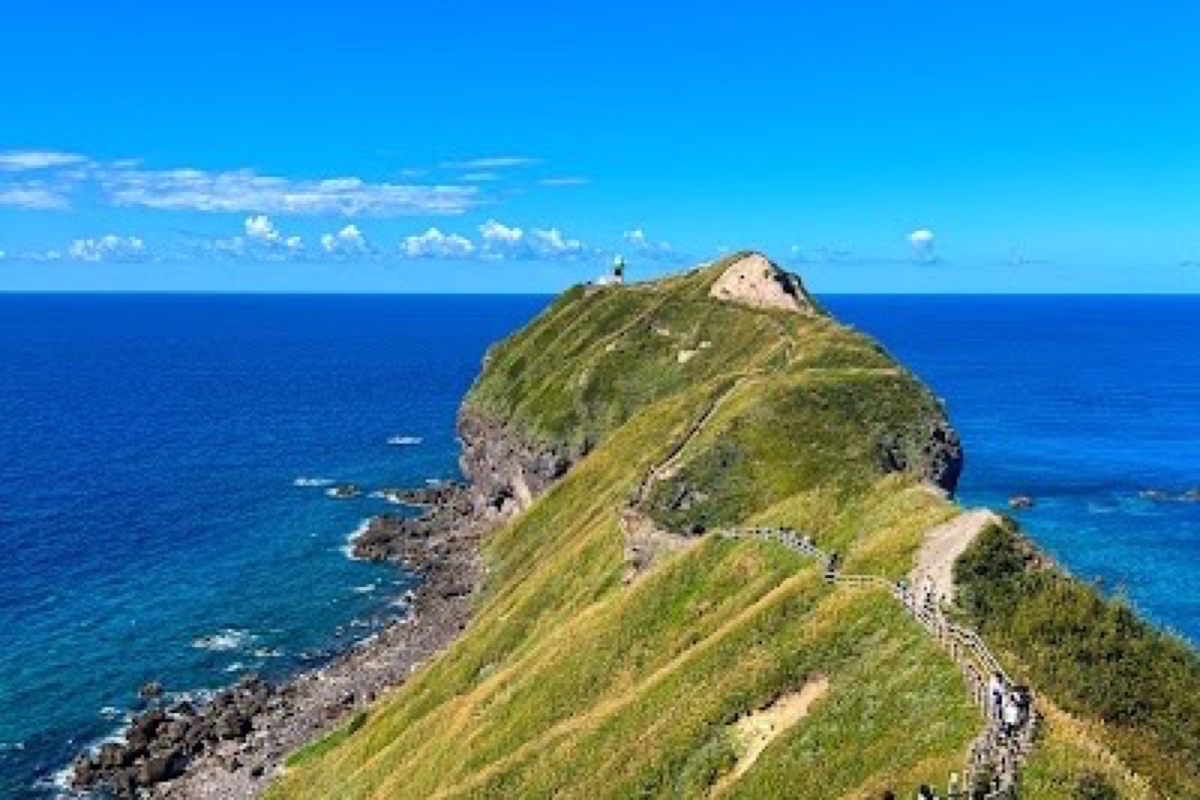 Cape Kamui lighthouse overlooking turquoise Shakotan Blue waters from coastal cliffs