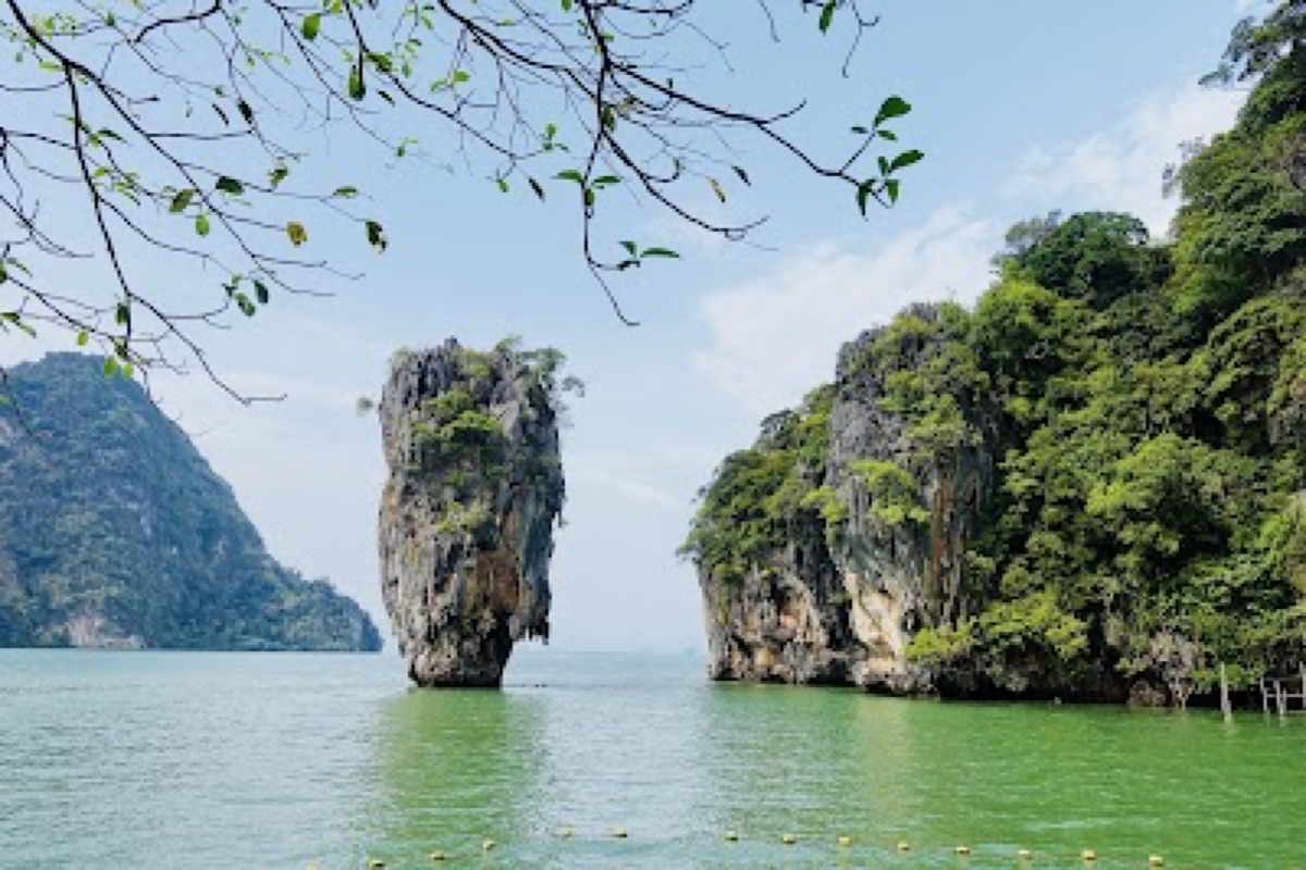 Phang Nga Bay longtail boat cruising past towering limestone karsts on emerald water