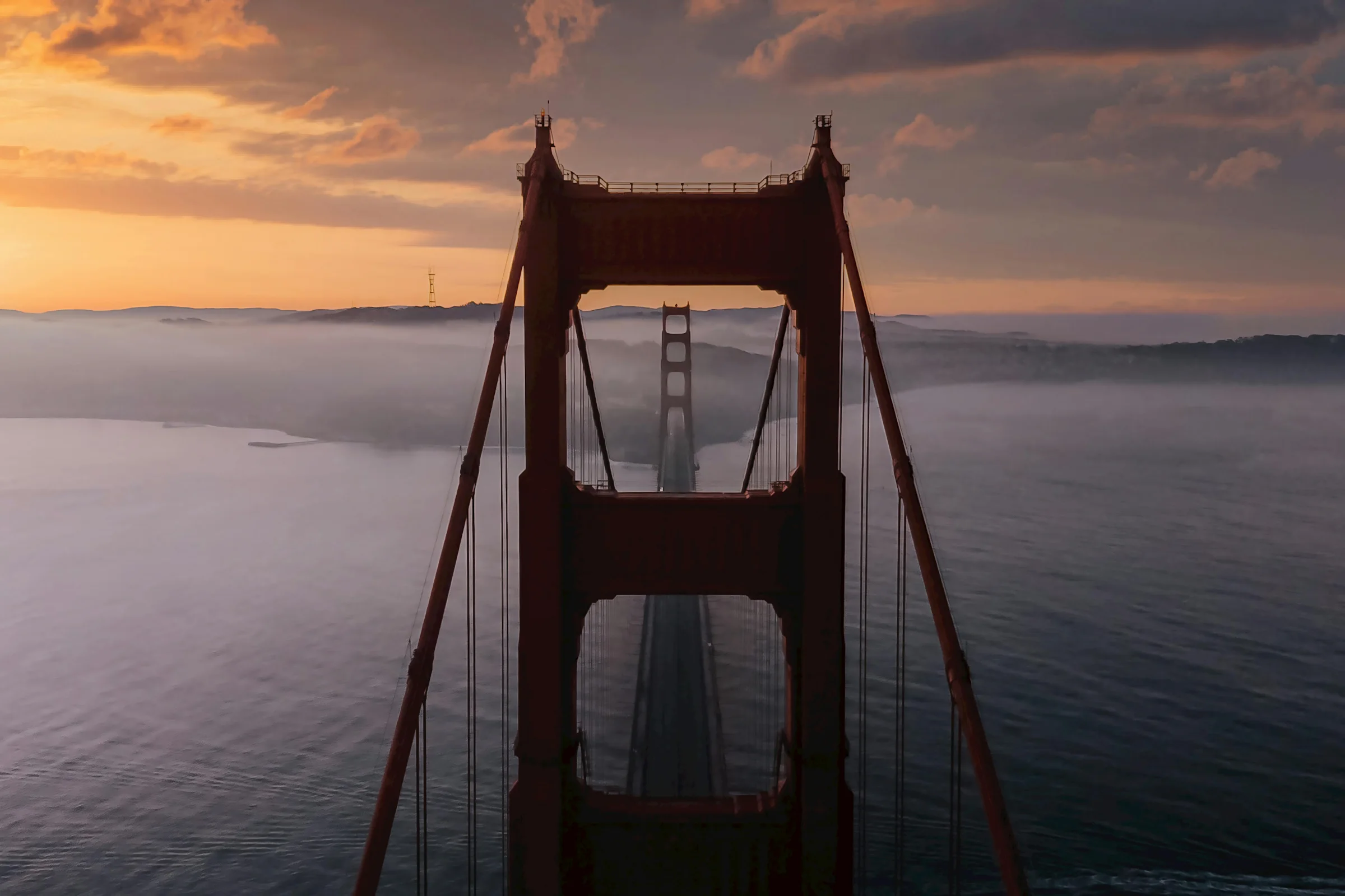 Sunrise view of the Golden Gate Bridge with the San Francisco skyline in the background.