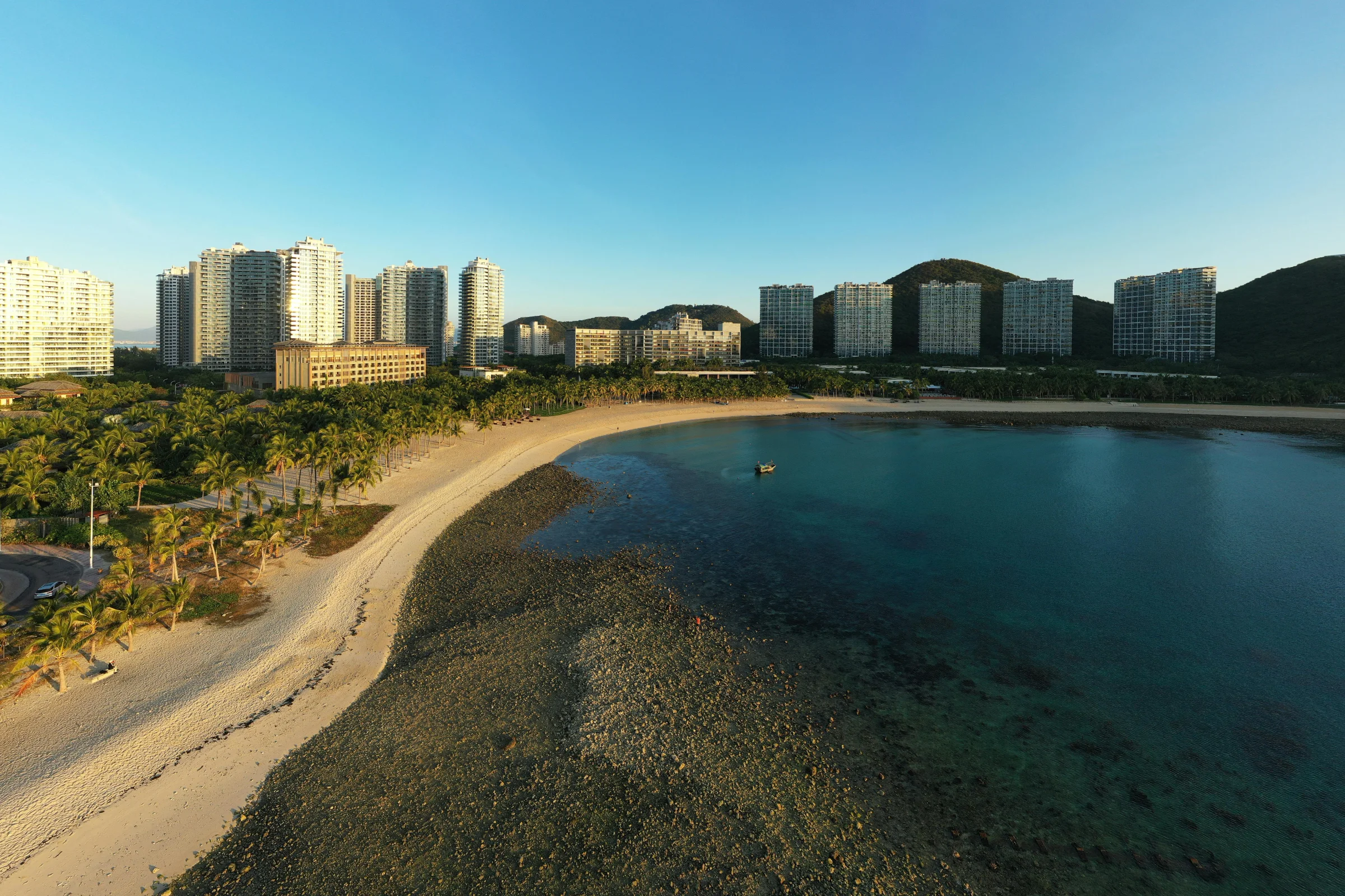 Aerial hero view of Sanya, Hainan with turquoise water, sandy beaches, and palm-lined coastline
