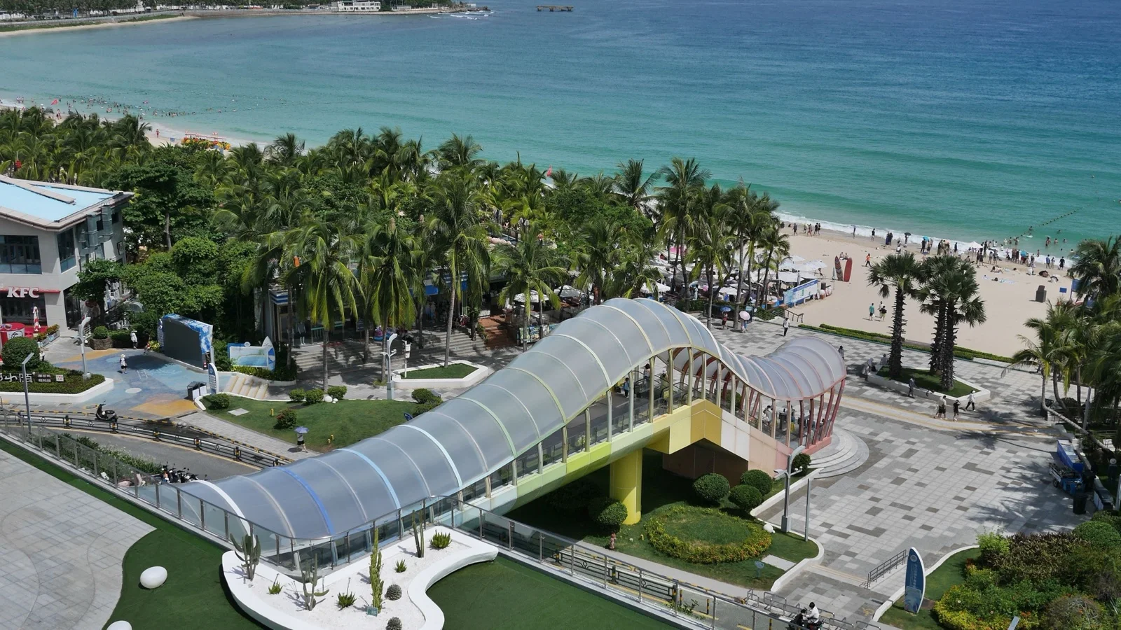 Aerial view of Yalong Bay crescent beach with turquoise water and palm trees in Sanya