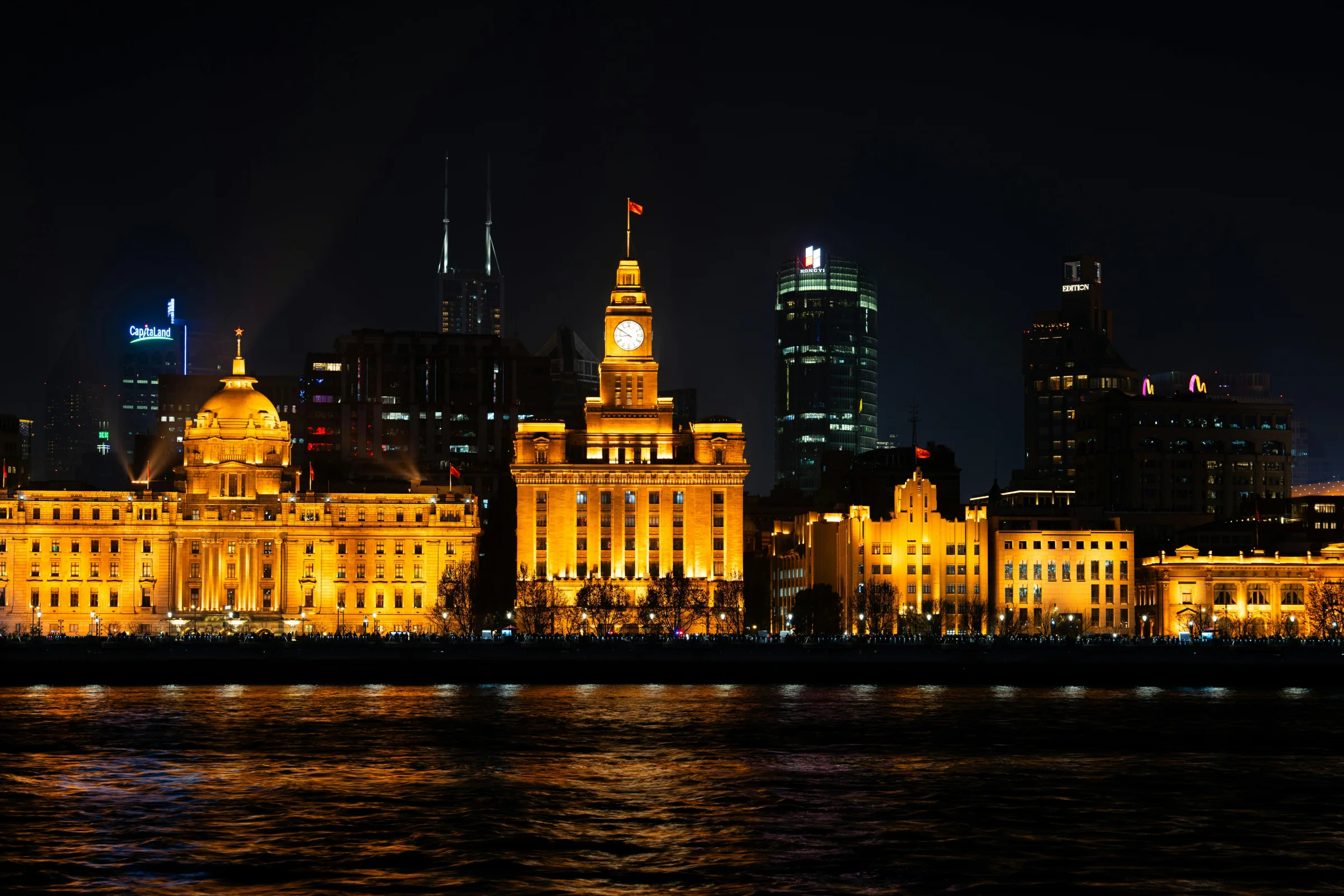 Night view of Shanghai skyline from the Bund waterfront with illuminated skyscrapers.