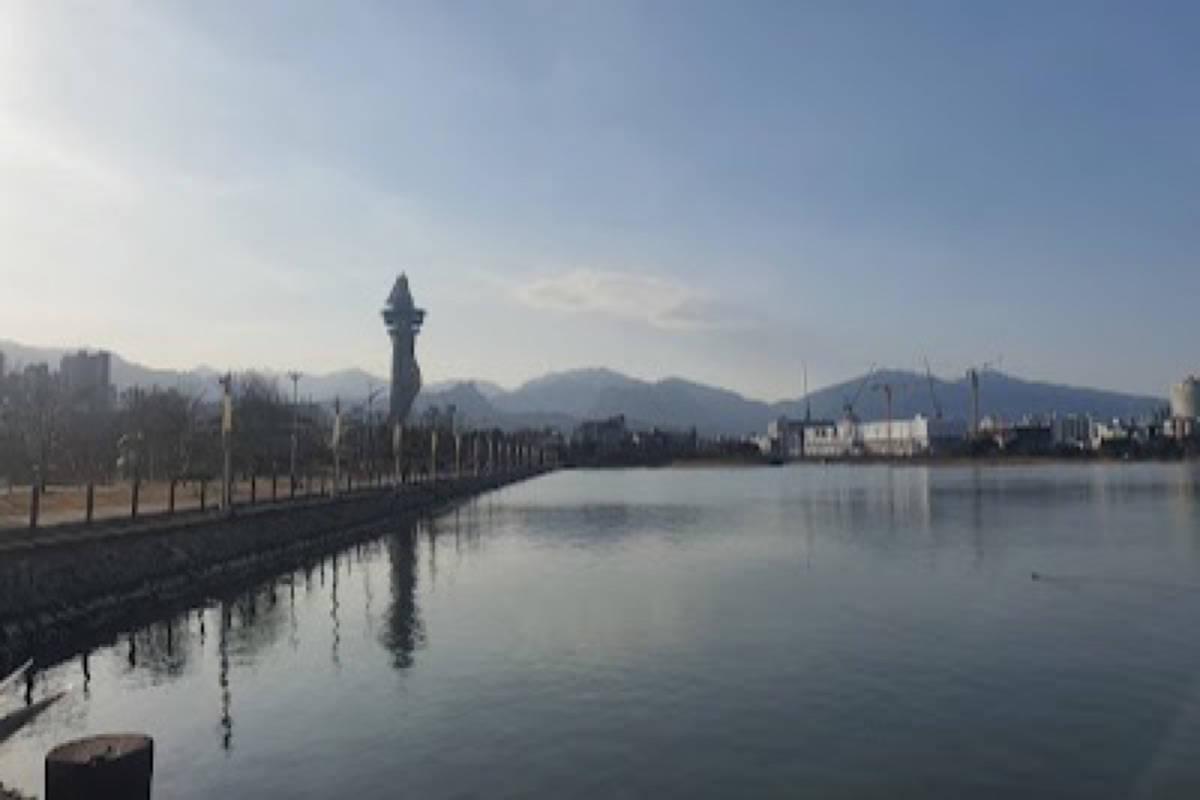 Cheongcho Lake calm evening water reflecting the lit-up Expo Tower with mountain backdrop in central Sokcho