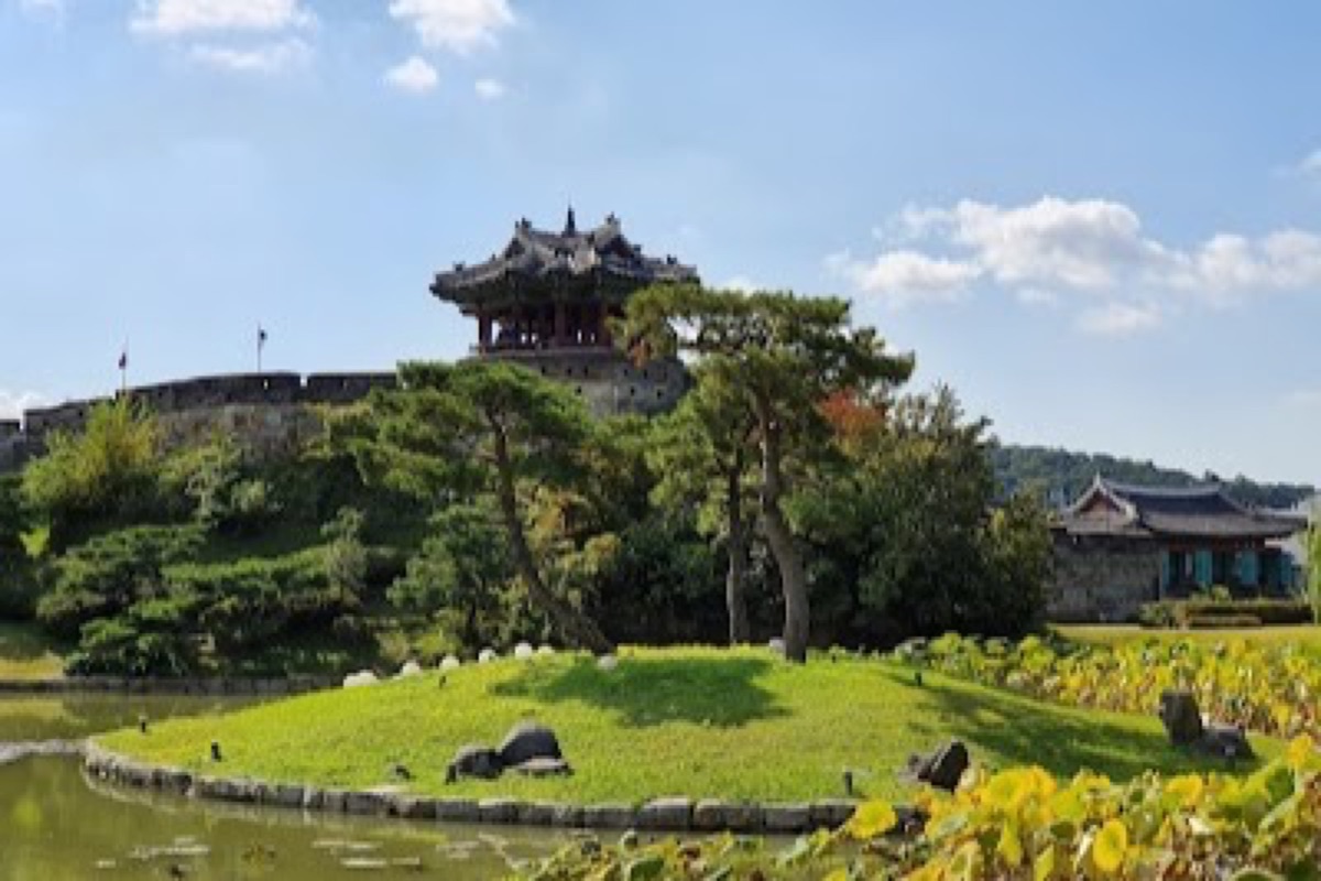 Banghwasuryujeong Pavilion overlooking Yongyeon Pond with willow trees and cherry blossoms on the Hwaseong Fortress wall in Suwon