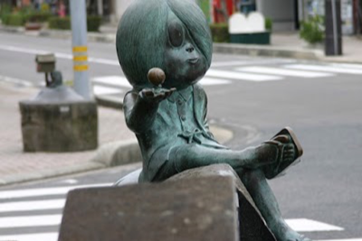 Bronze yokai monster statues lining Mizuki Shigeru Road in Sakaiminato at dusk