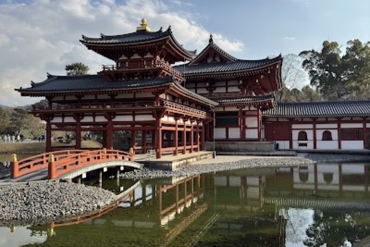 Byodoin Phoenix Hall reflected in the mirror pond surrounded by temple grounds in Uji