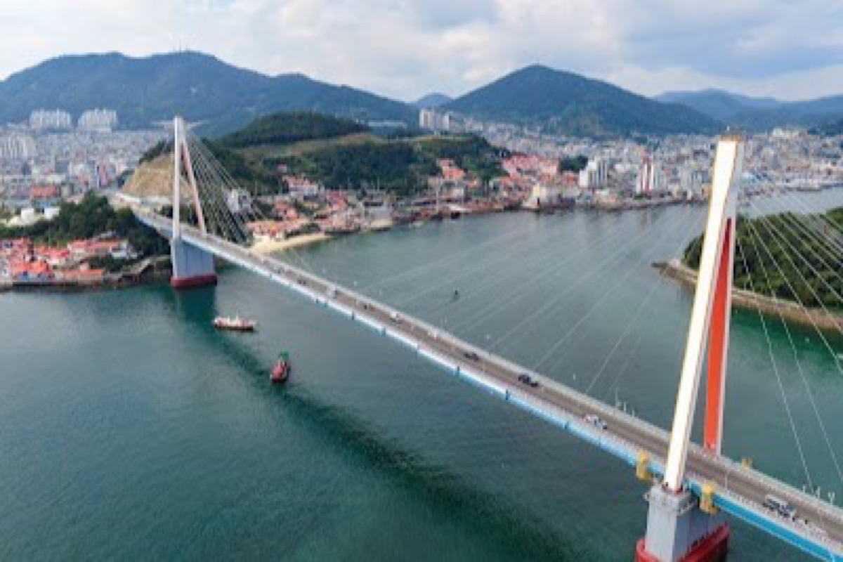 Dolsan Bridge illuminated in rainbow colors at night over the Yeosu harbor waterfront